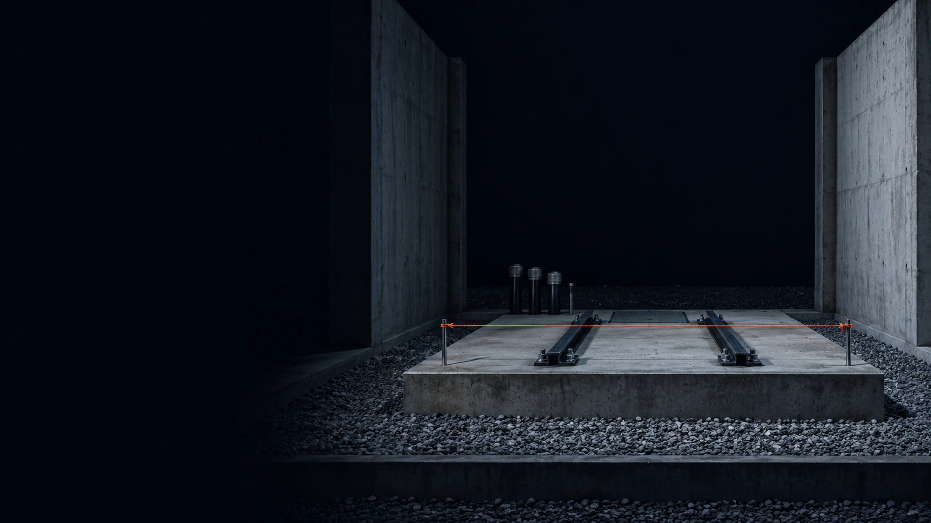 An empty transformer bay at night: a bare concrete plinth with steel rails between two firewalls, a taut coral line marking where the new tank will stand.